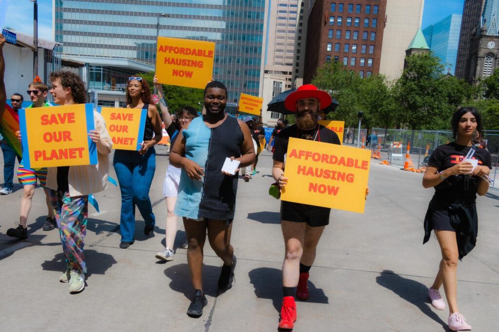 HOT in cleveland pride marching holding signs for affordable hausing and saving the planet (climate change) and more