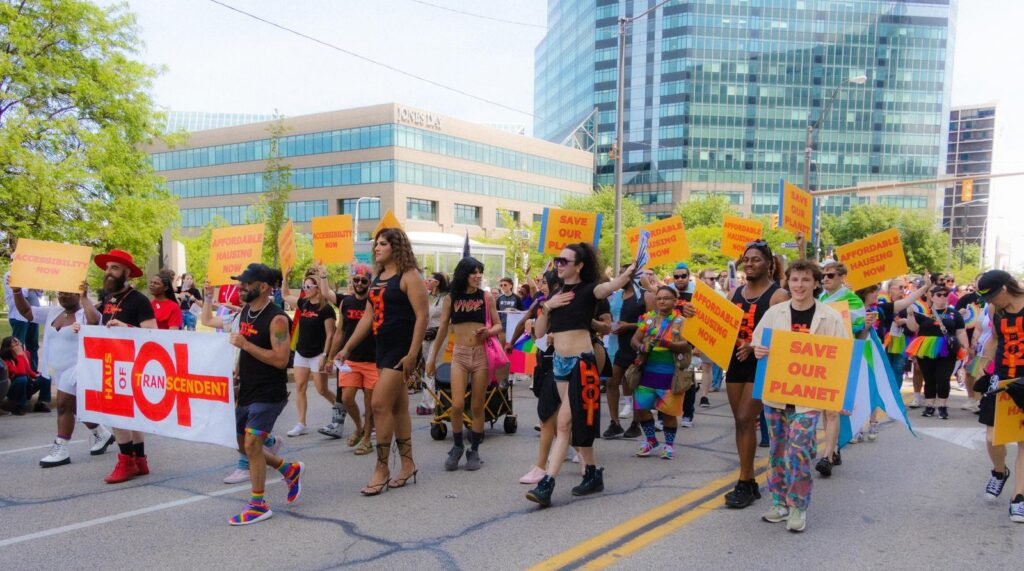 HOT in cleveland pride marching holding signs for affordable hausing and saving the planet (climate change) and more