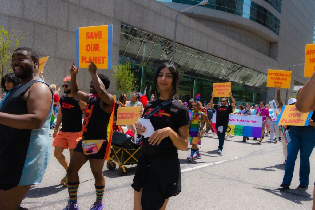 HOT in cleveland pride marching holding signs for affordable hausing and saving the planet (climate change) and more